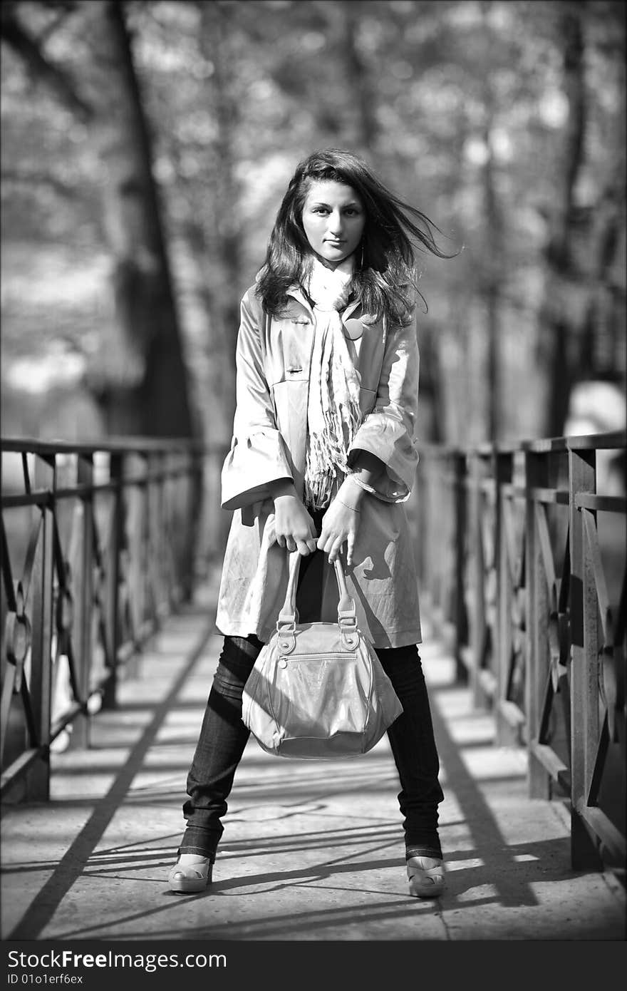 Young beautiful woman in a raincoat with a bag in hands. Young beautiful woman in a raincoat with a bag in hands