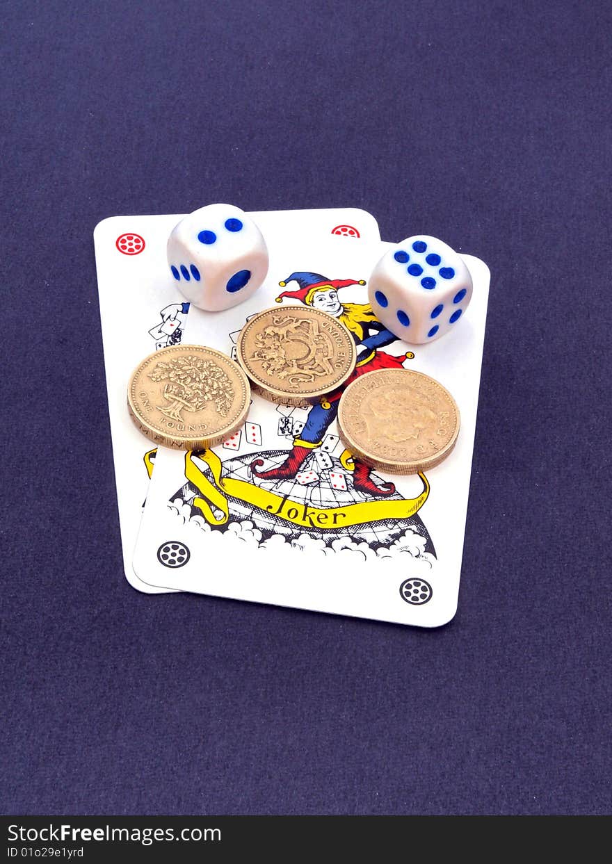 Concept of gambling showing coins, the joker playing cards and dice. Concept of gambling showing coins, the joker playing cards and dice.