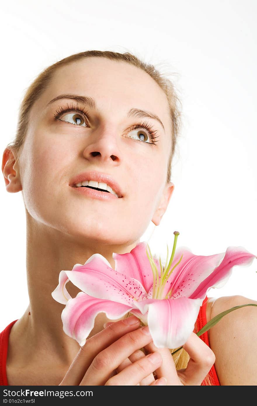 A portrait of a nice blond girl in red with a pink lily near her face on a white background. A portrait of a nice blond girl in red with a pink lily near her face on a white background