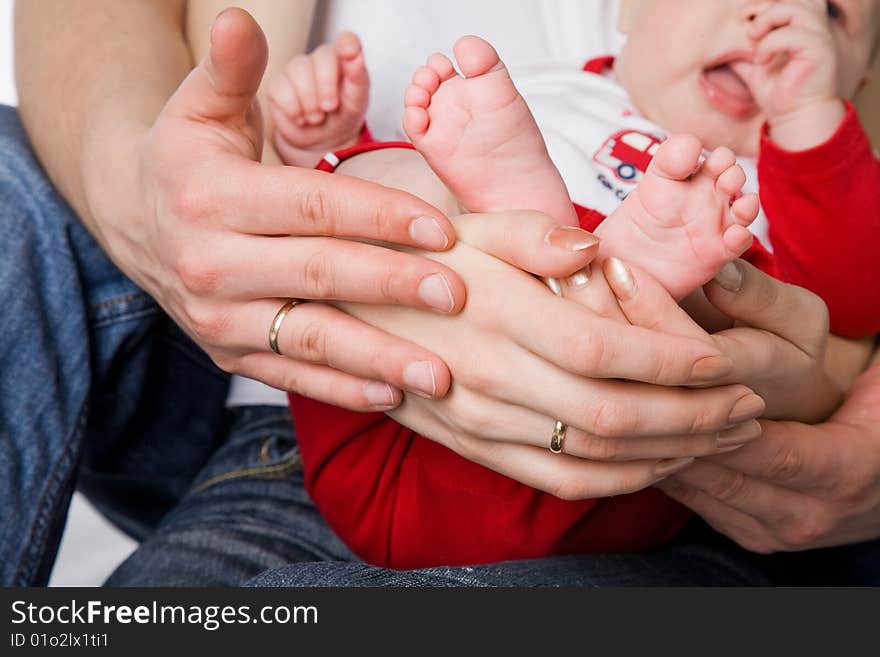 Mother and father holding litttle legs of their child studio shot. Mother and father holding litttle legs of their child studio shot