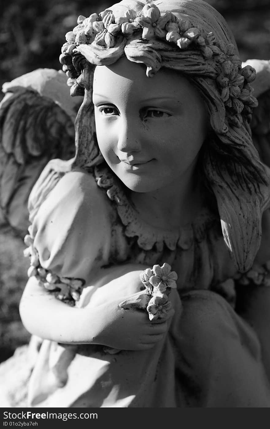 A statue of a young female angel holding flowers and smiling. A statue of a young female angel holding flowers and smiling