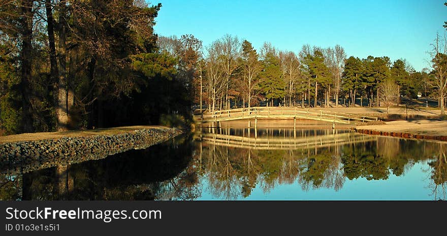 A landscape image with a reflection of a bridge and trees. A landscape image with a reflection of a bridge and trees.