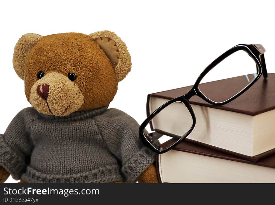 Teddy bear, glasses and a pile of old books on a white background