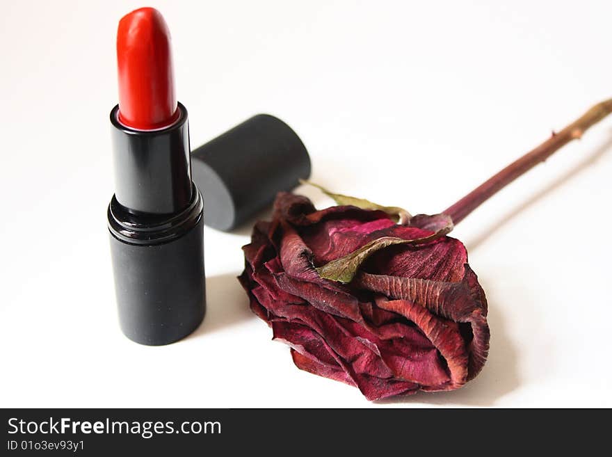 Red lipstick and a dried rose with white background. Red lipstick and a dried rose with white background