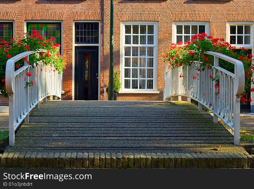 Old bridge railings that are decorated with boxes of flowers on a background of a typical Dutch house