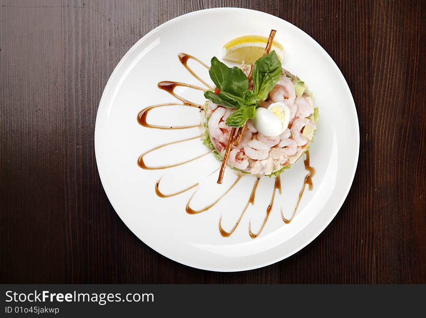 Plate with shrimp salad on brown table with clipping path