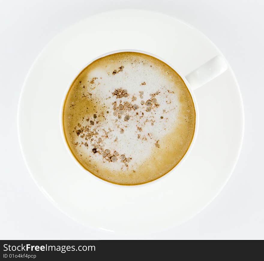 Cup of coffee, latte or cappuccino on a white plate topped with cocoa or chocolate from above isolated on white background