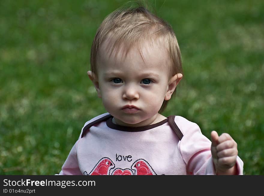 Frowning baby girl playing outdoors. Frowning baby girl playing outdoors