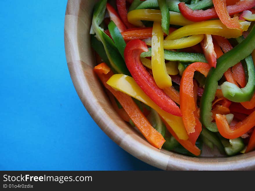 Red green orange and yellow peppers cut up inside a salad bowl. Red green orange and yellow peppers cut up inside a salad bowl