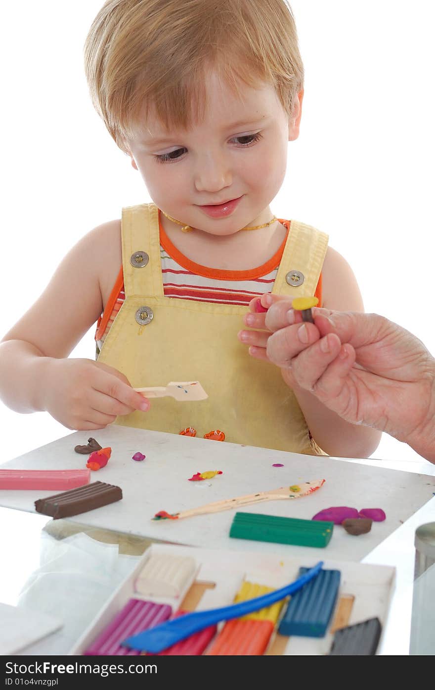 Little boy playing with many-coroled plasticine