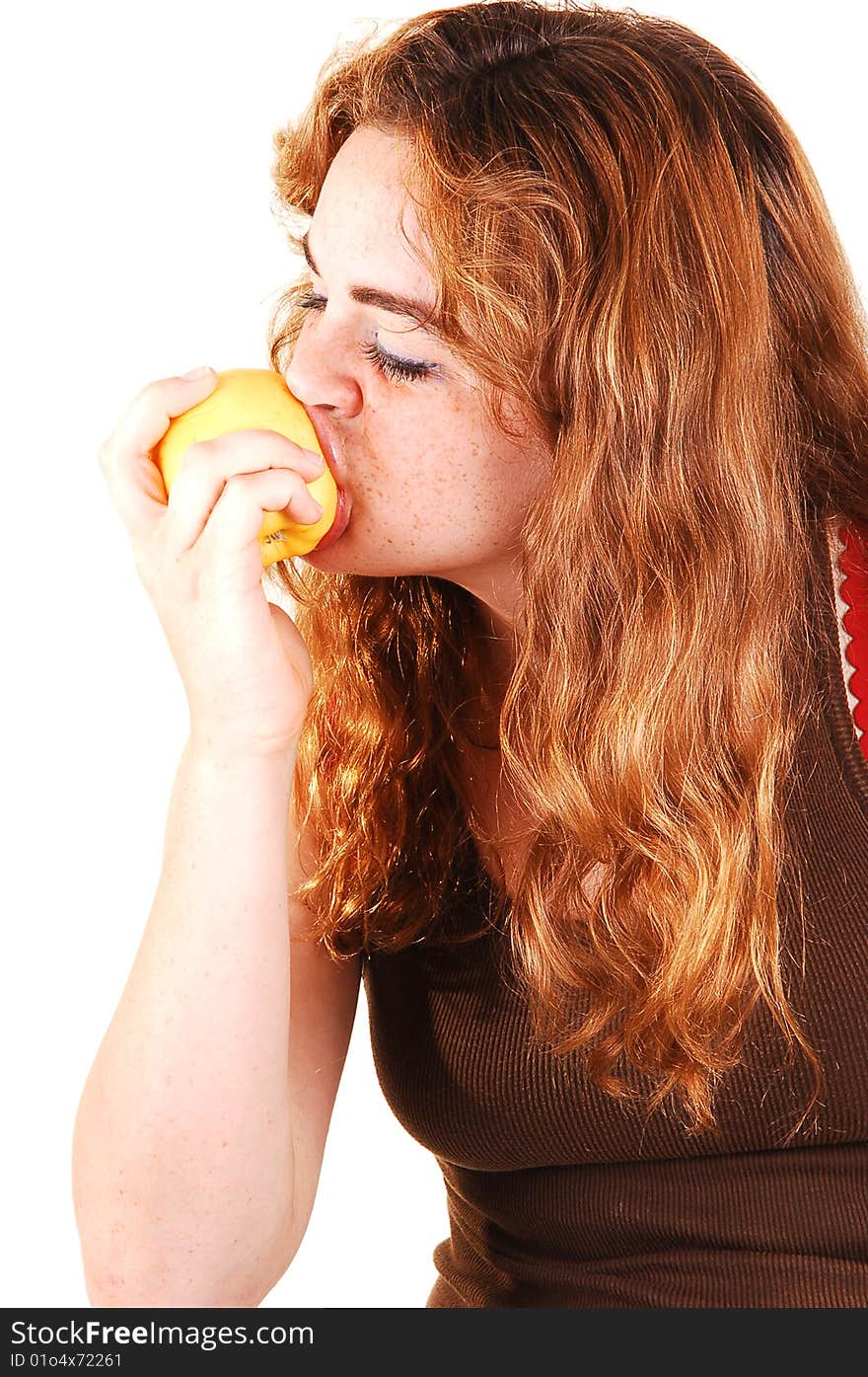 Pretty girl with long bright red hair eating an yellow apple and really enjoying the fruit. Pretty girl with long bright red hair eating an yellow apple and really enjoying the fruit.