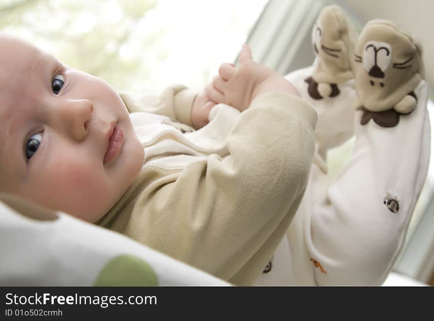 Infant lying down with feet up in the air, looking at the camera. Infant lying down with feet up in the air, looking at the camera