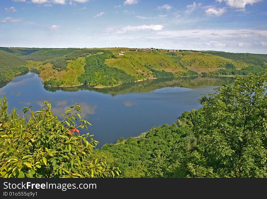 Meandering river in high green banks and summer panorama