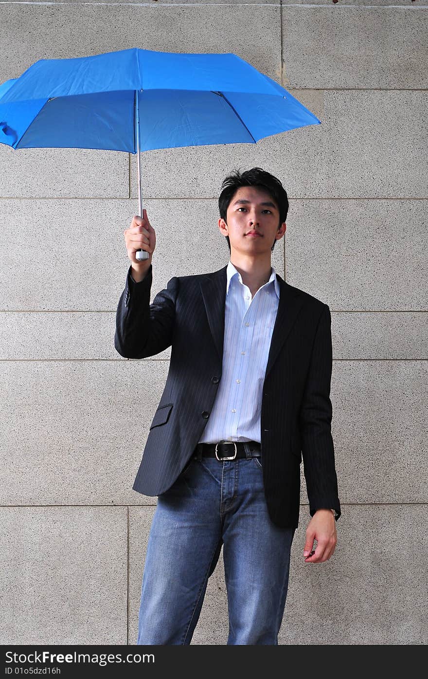 Sasual Asian man with blue umbrella. Sasual Asian man with blue umbrella.