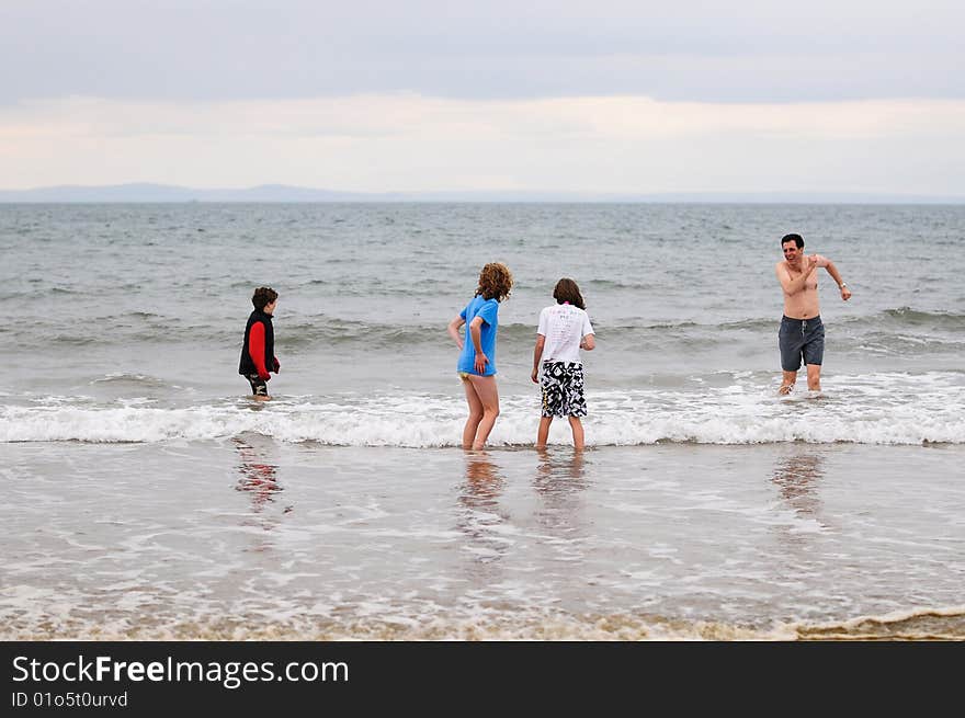 Father And Children Wading In Cold Sea