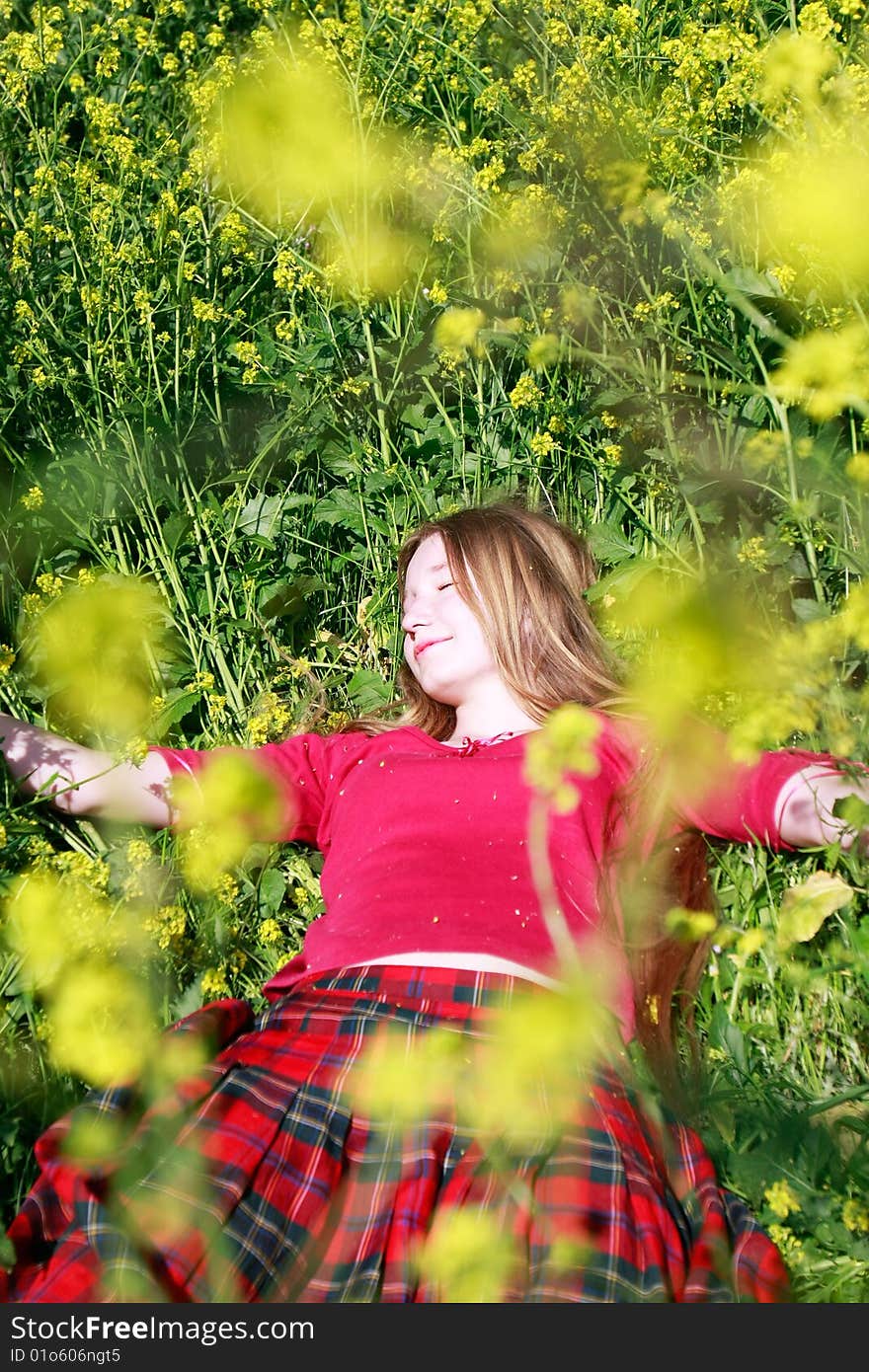 Pretty girl in green grass and yellow flowers