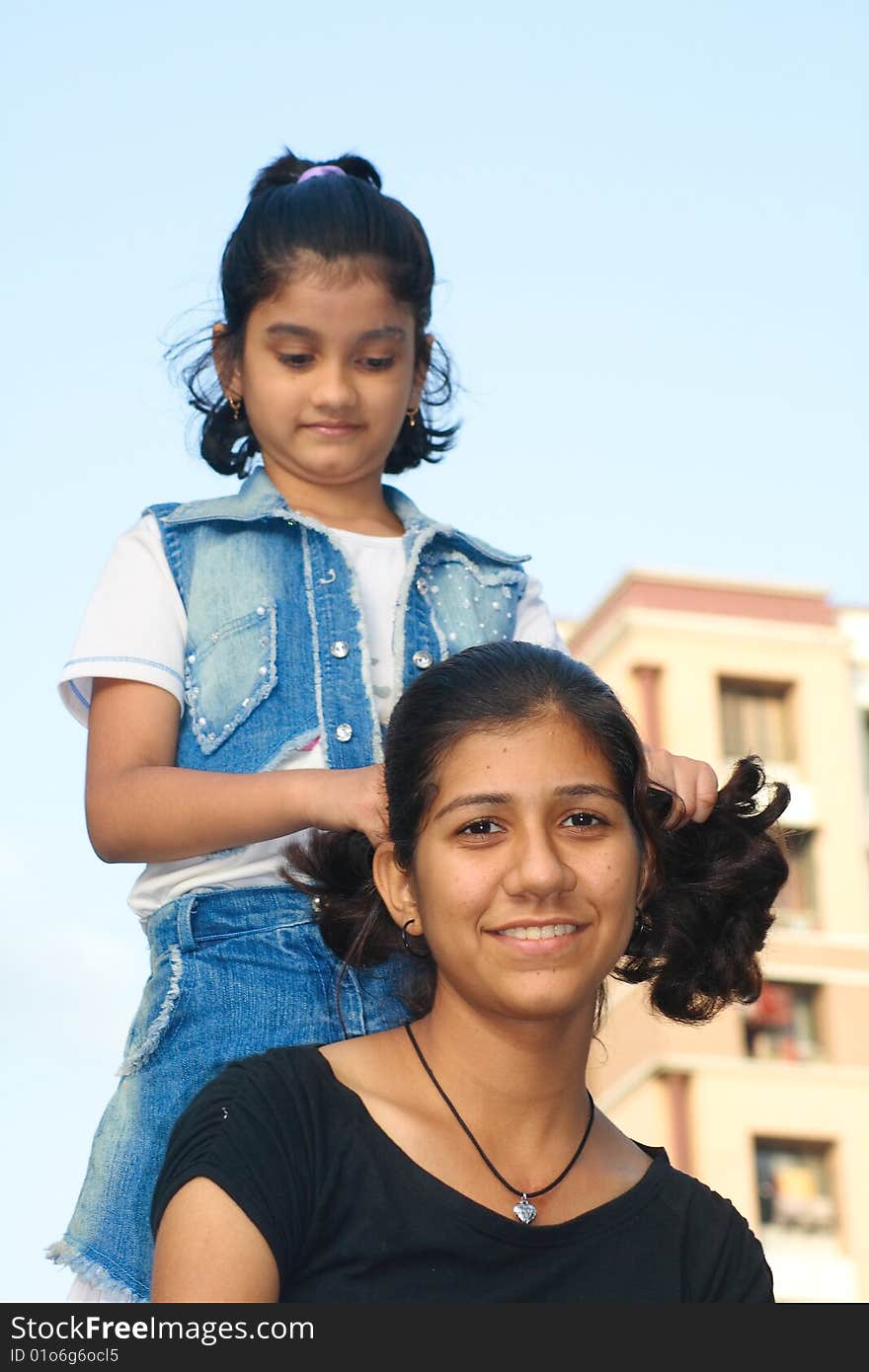 A small girl adjusting hairs of her teenager friend. A small girl adjusting hairs of her teenager friend.