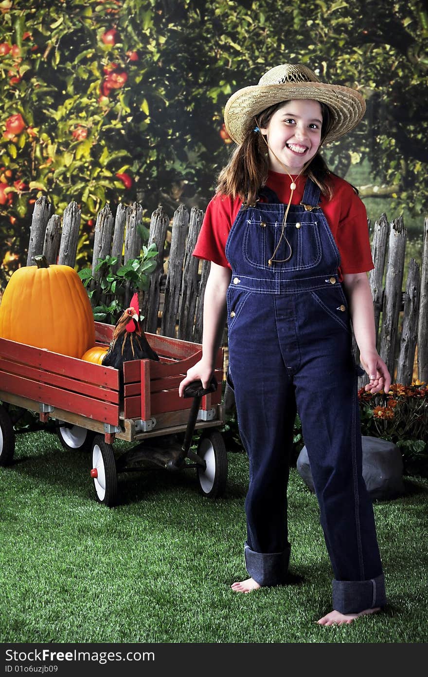 A happy, barefoot girl pulling a wagon with pumpkins and a rooster past an apple orchard. A happy, barefoot girl pulling a wagon with pumpkins and a rooster past an apple orchard.