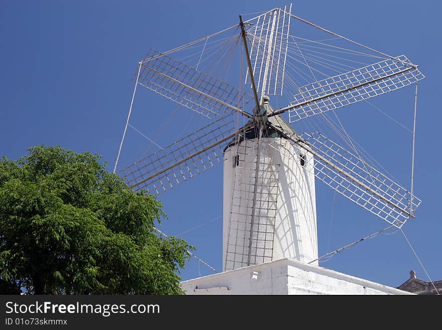 White historic ancient wind-mill in the streets of a town in Balearics. White historic ancient wind-mill in the streets of a town in Balearics