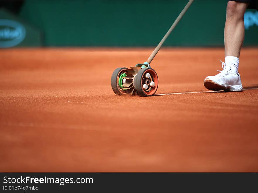 A boy a painting a new court line. A boy a painting a new court line