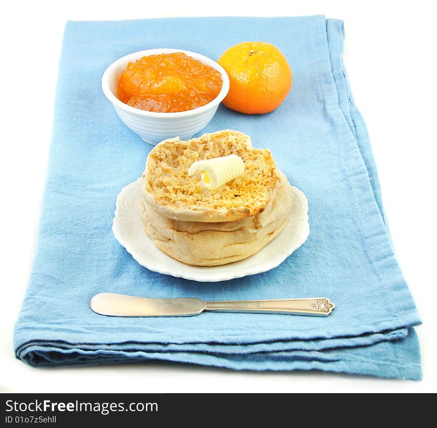 Buttered english muffin and marmalade on blue cloth background. Buttered english muffin and marmalade on blue cloth background.