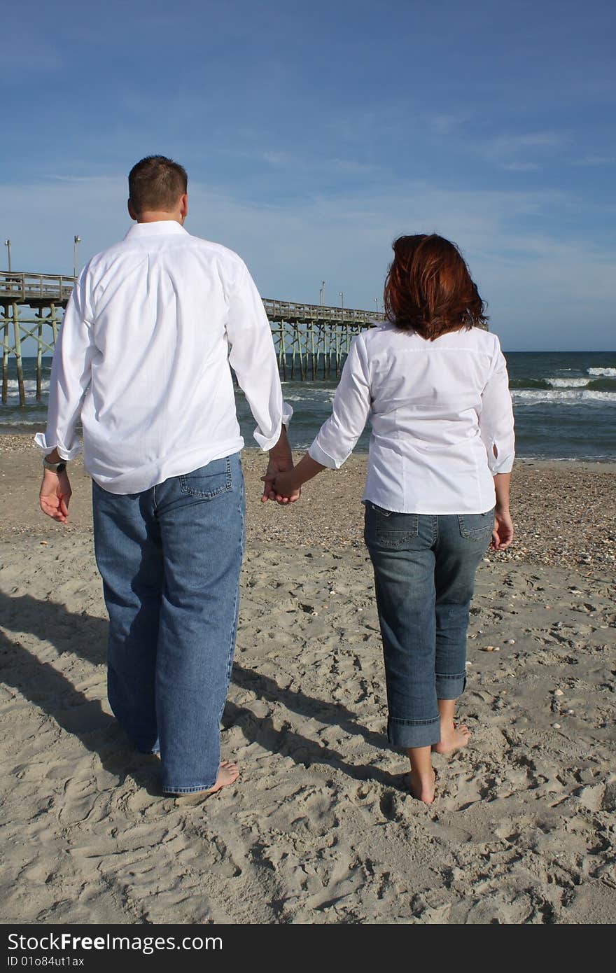 A young couple walking on the beach barefoot