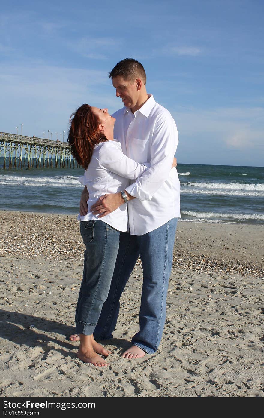 A young couple enjoying time together at the beach looking at each other. A young couple enjoying time together at the beach looking at each other.