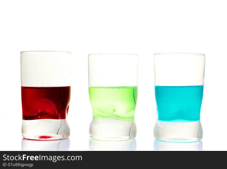 Three red green blue drinks in glasses on a white background