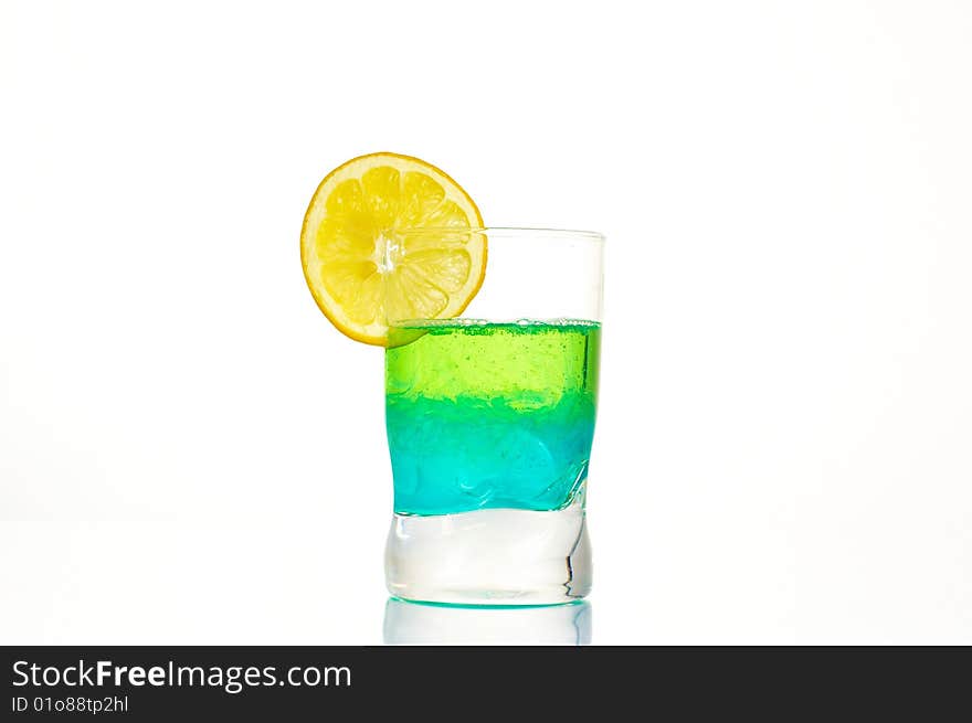 A colorful dring in a glass on a white background, with a lemon on the top. A colorful dring in a glass on a white background, with a lemon on the top