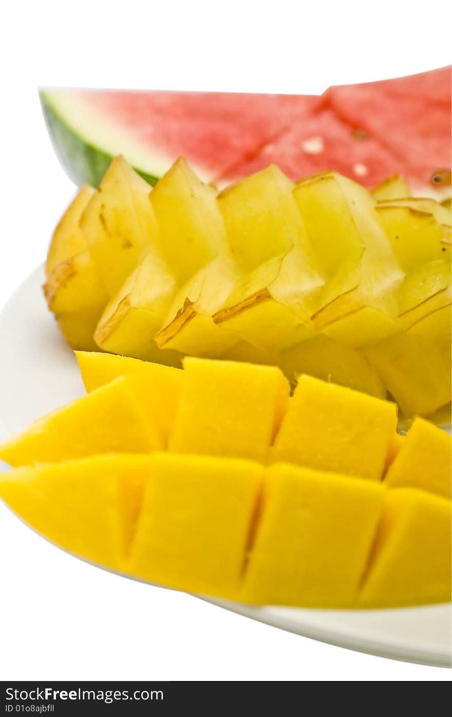 Three types of tropical fruits sliced and arranged on a white plate: mango, starfruit and watermelon. Three types of tropical fruits sliced and arranged on a white plate: mango, starfruit and watermelon.