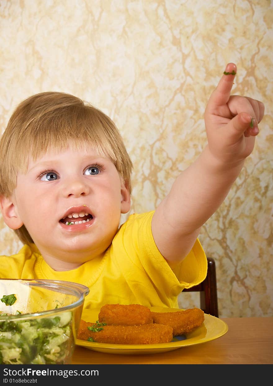 The little boy eats fresh salad. The little boy eats fresh salad