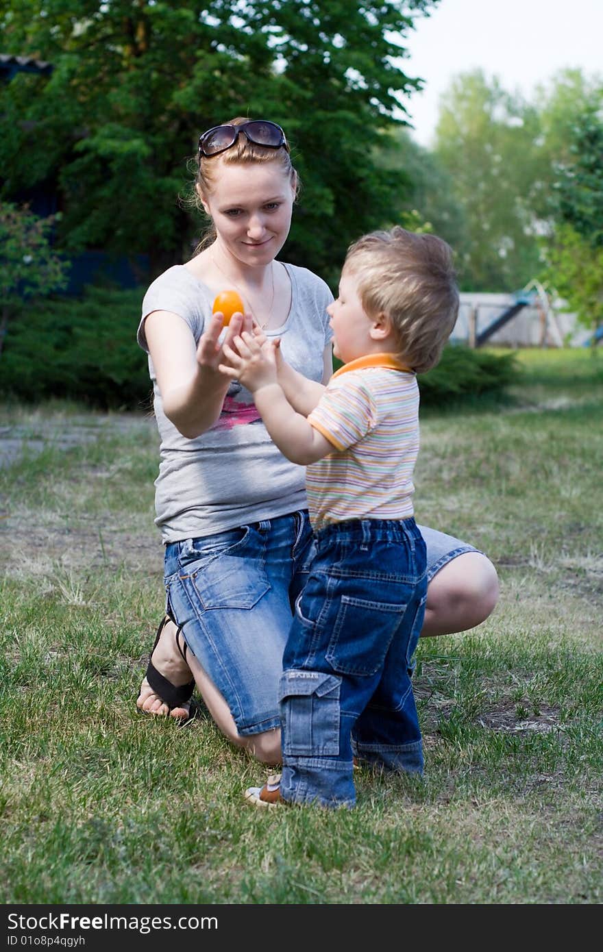 Mother and son playing on the grass in the yard of the house. Mother and son playing on the grass in the yard of the house.