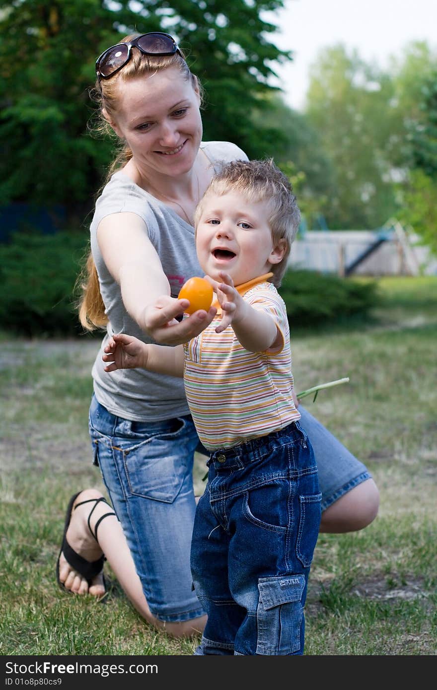 Mother and son playing on the grass in the yard of the house. Mother and son playing on the grass in the yard of the house.