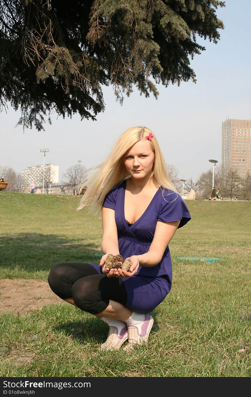 Girl sitting under fir tree in a city park