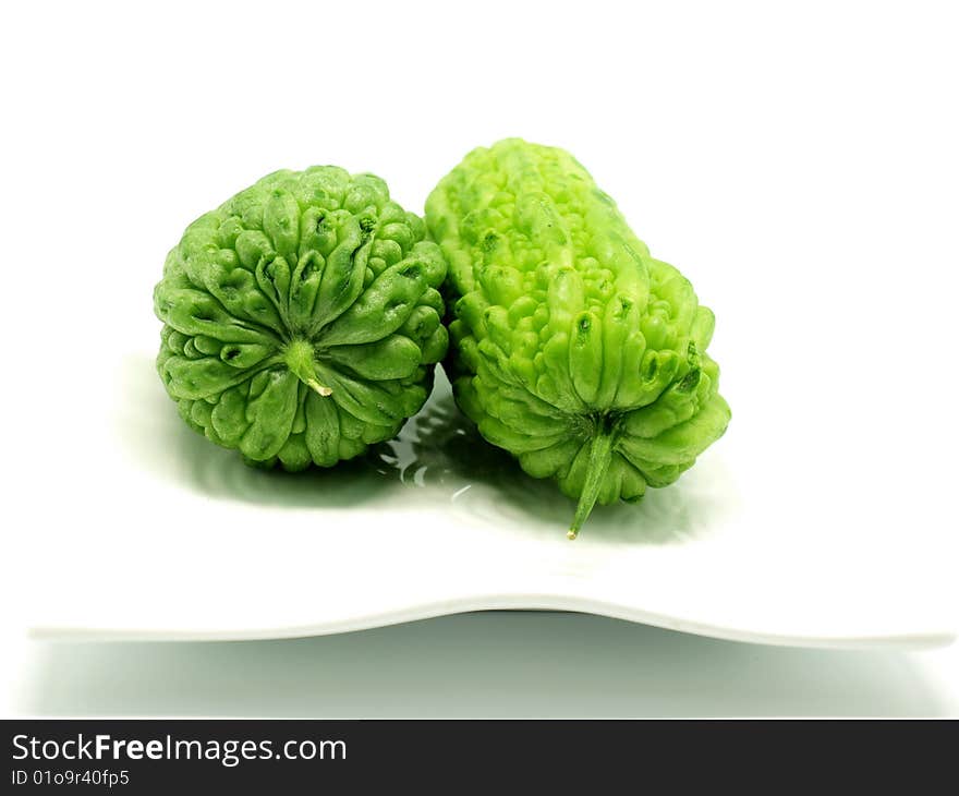 Two bitter melon on whtie plate isolated on white background.