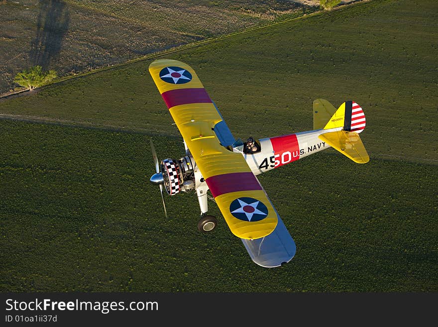 Yellow 1942 steerman flying over field. Yellow 1942 steerman flying over field