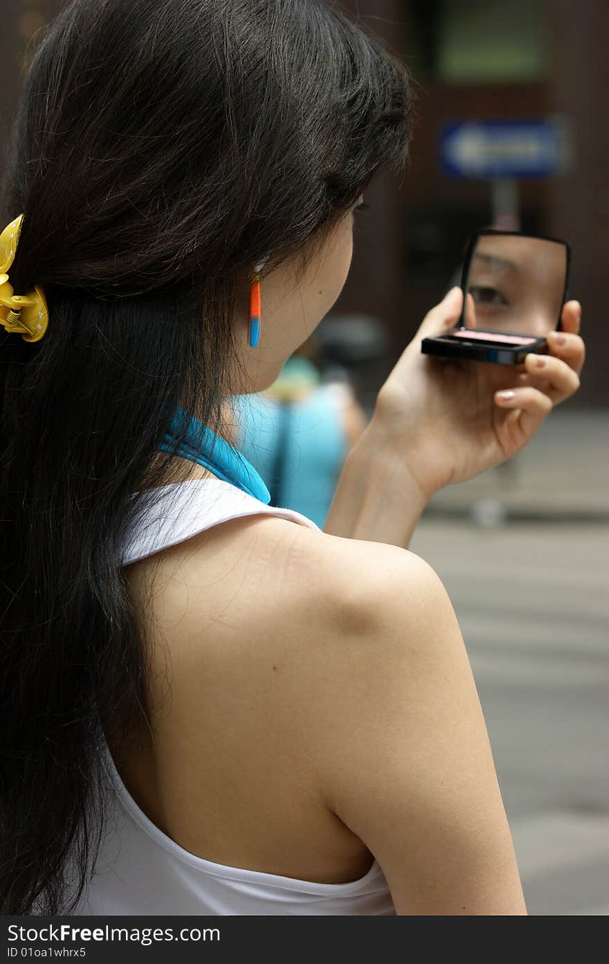 A young Woman with a lipstick mirror on the road.