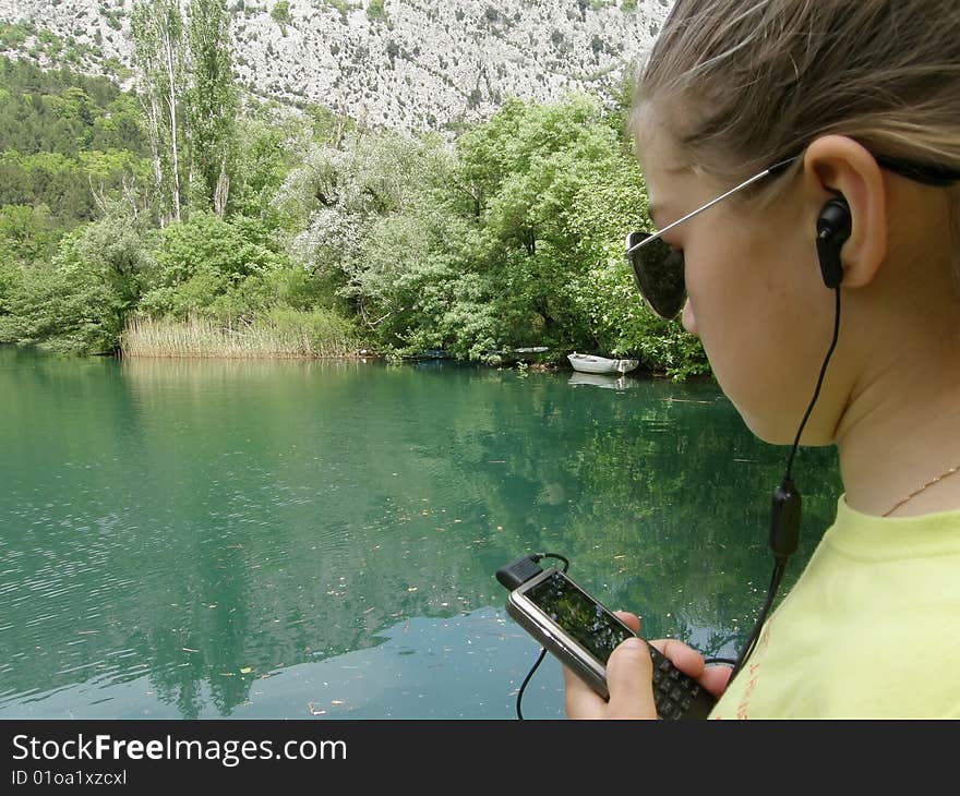 Girl listening music on cellular in the river. Girl listening music on cellular in the river