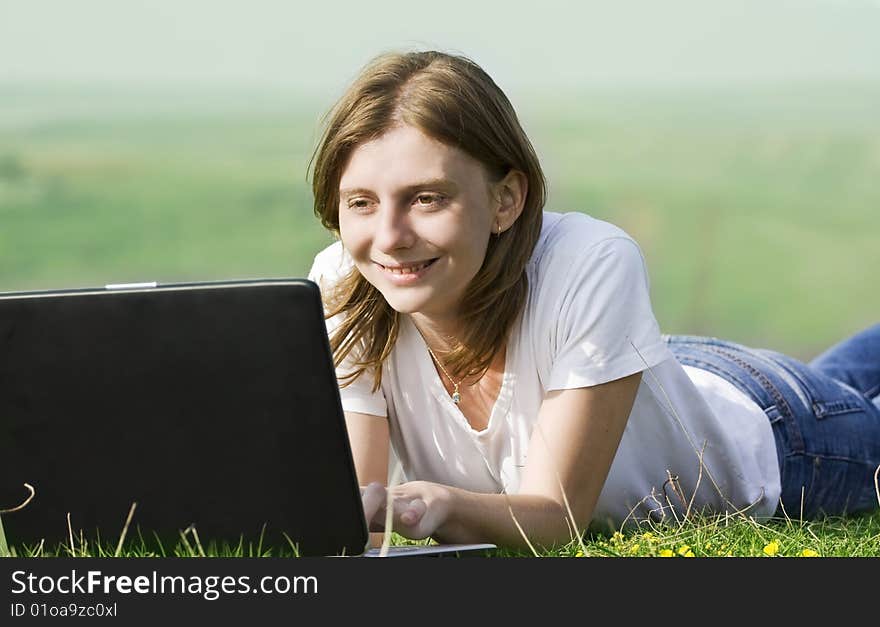 Young blonde girl working on laptop outdoors. Young blonde girl working on laptop outdoors