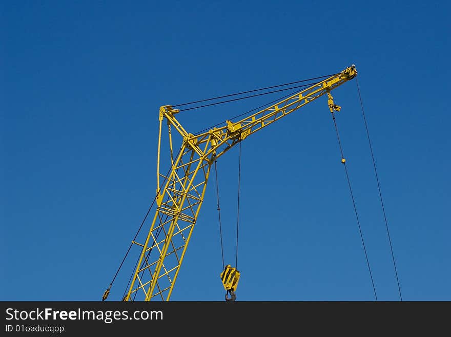 Yellow industrial crane on blue sky background. Yellow industrial crane on blue sky background