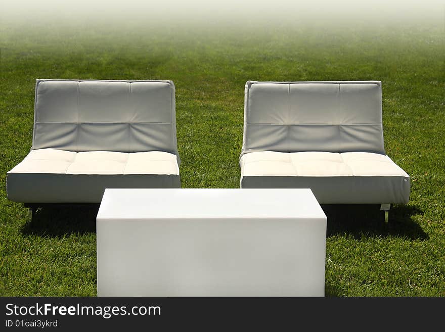 Modern white chairs and table in lawn with faded white background