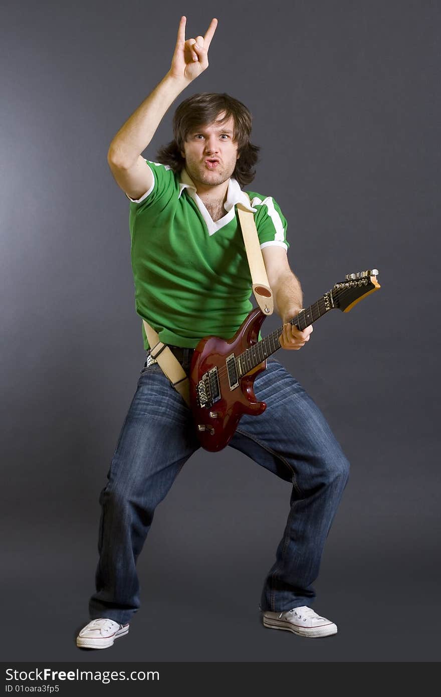 Guitarist playing on black background with one hand in the air