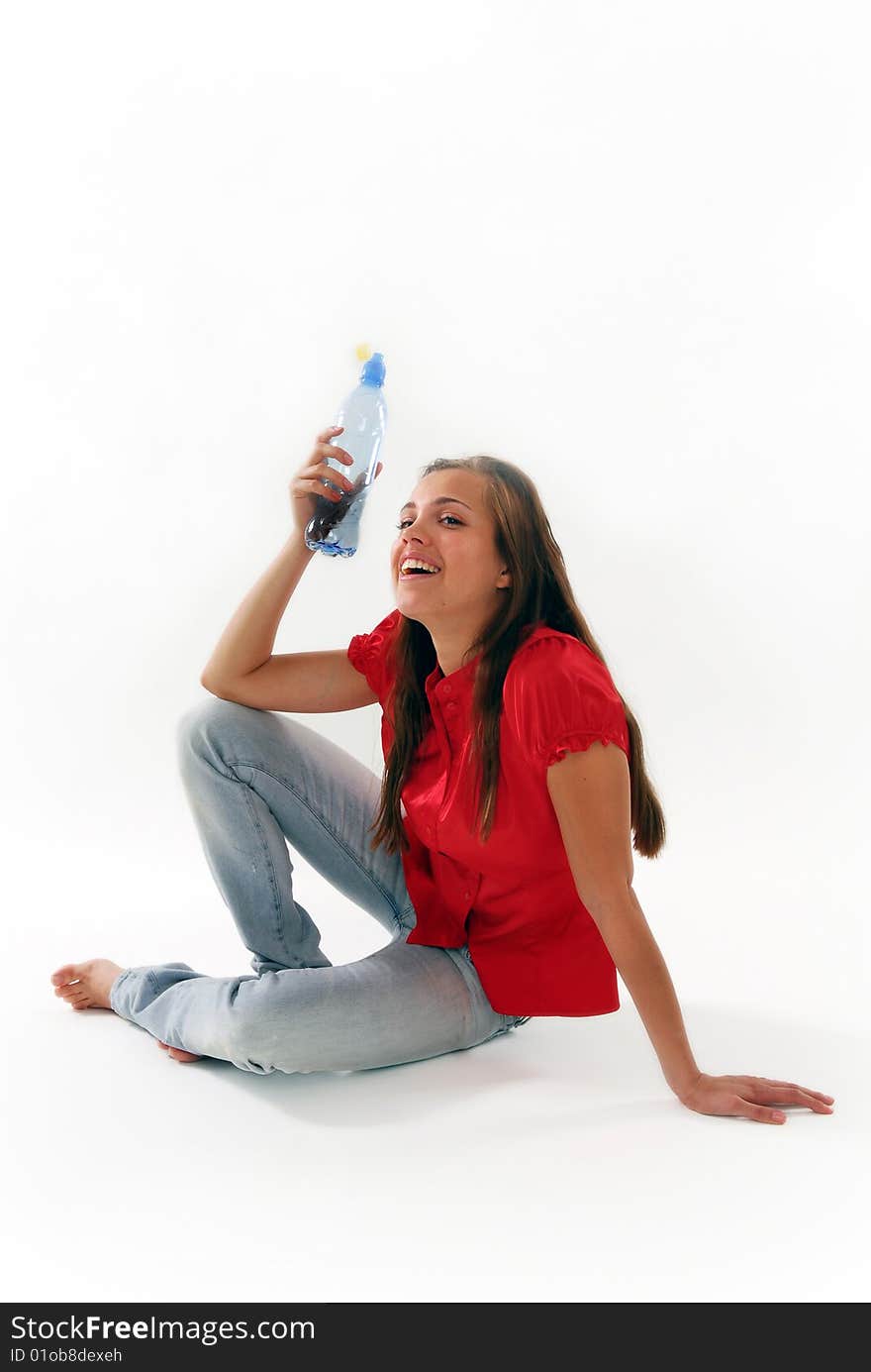 The woman sitting on a floor with a water bottle on a white background. The woman sitting on a floor with a water bottle on a white background