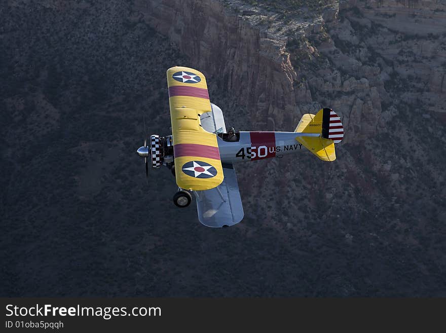 Yellow 1942 steerman flying over large rock canyon. Yellow 1942 steerman flying over large rock canyon.