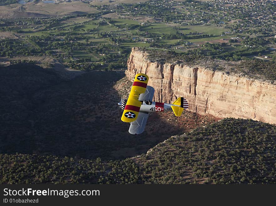 Yellow biplane over large canyon