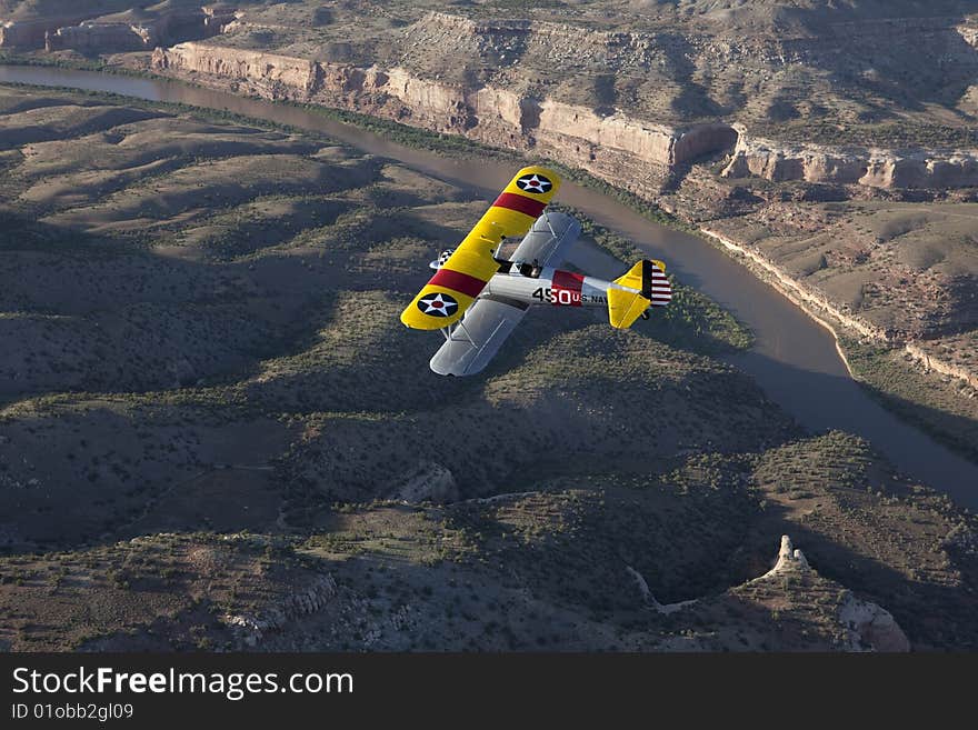 Yellow biplane over river