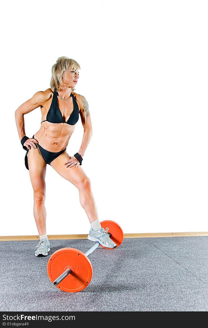 Young woman bodybuilder stands and leans against the weight. Young woman bodybuilder stands and leans against the weight