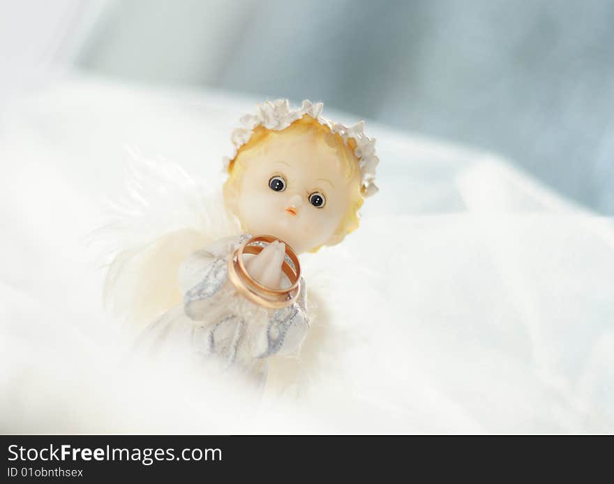 Photo of a figure of a little angel with gold wedding rings