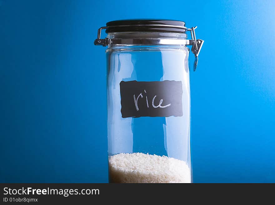 Inscription Rice on transparent glass jar. Over blue background