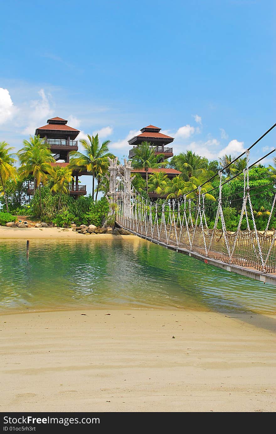 Wooden suspension bridge leading to paradise island, with hotels in the background. Wooden suspension bridge leading to paradise island, with hotels in the background